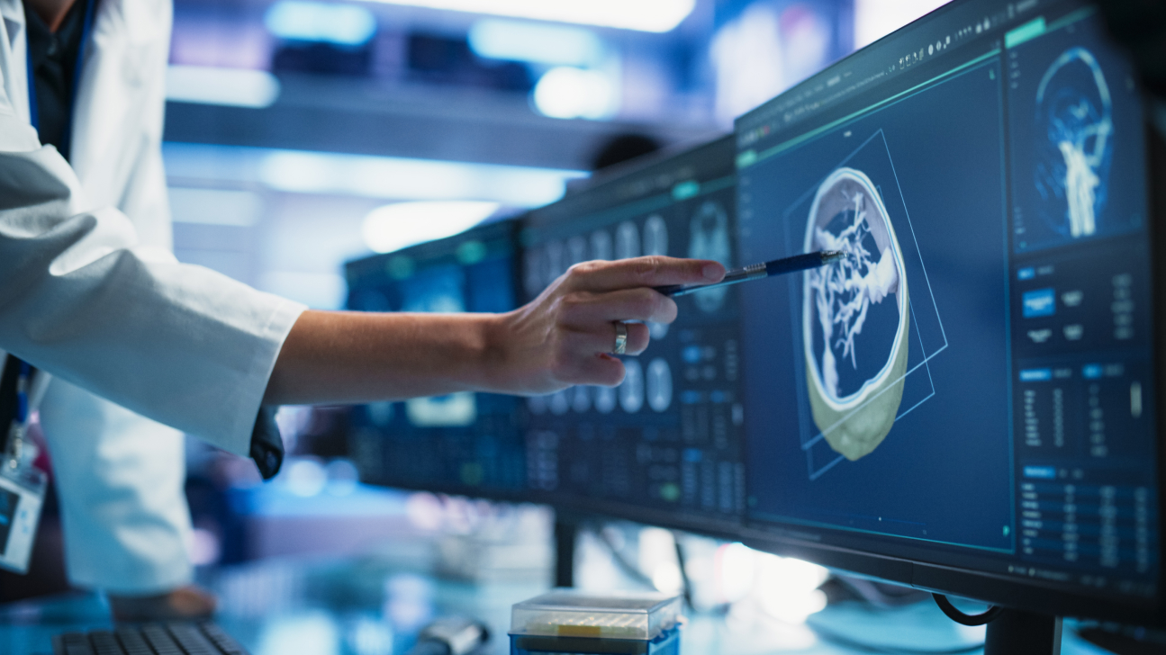 A radiologist looks at scans and patient data on a computer screen.